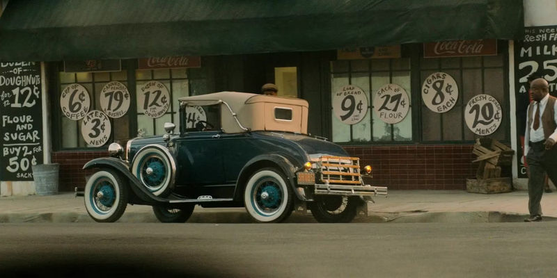A blue sedan parked in front of a general store in Perry Mason.