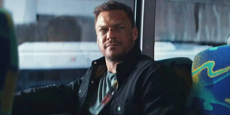 Alan Ritchson smiling on a bus as Jack Reacher in the Reacher season 2 finale