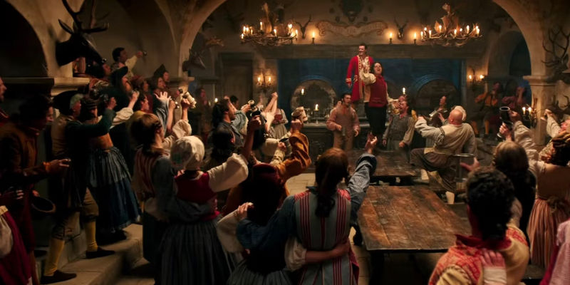 Gaston (Luke Evans) singing in front of a crown of people cheering in Beauty and the Beast.