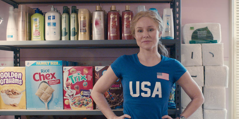 Kristen Bell standing in front on products in Queenpins - Broadway Debut: The Adventures of Tom Sawyer