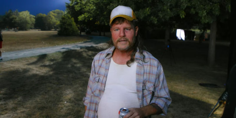 Matt Damon as a red-faced, mulleted, beer-bellied redneck, wearing a baseball cap and holding a beer in Deadpool 2 - Drive-Away Dolls Continues Matt Damon's Random Movie Cameo Trend