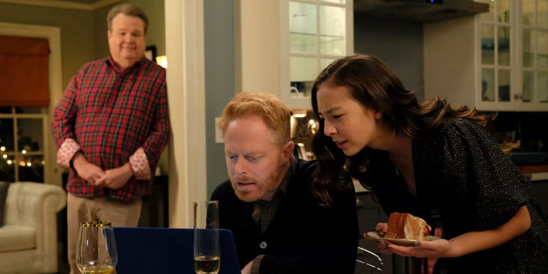 Lily and Mitch looking at a laptop while Cam watches them in the Modern Family episode The Last Christmas