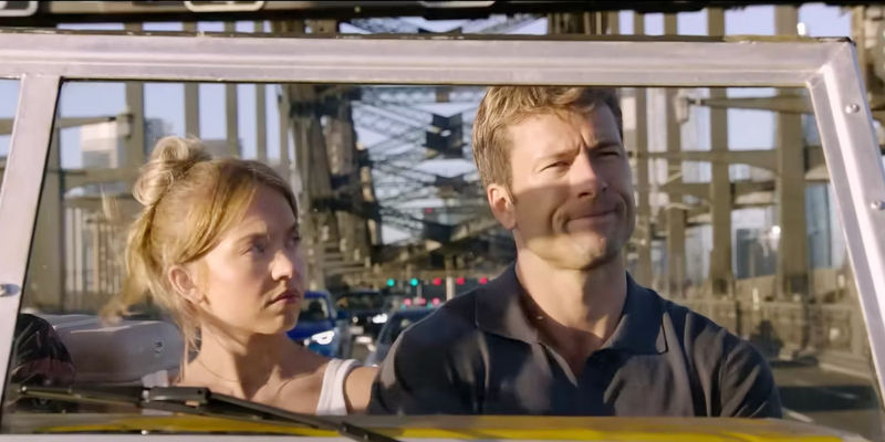 Sydney Sweeney's Bea and Glen Powell's Ben sit next to each other in a car and look annoyed in Anyone But You.