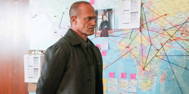 Stabler standing in front of a pinboard of a map in What Happens in Puglia