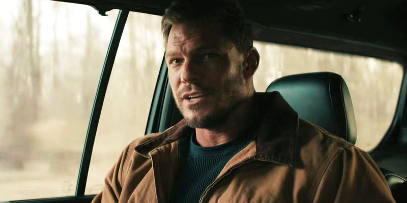 Alan Ritchson in the car talking to his team in Reacher
