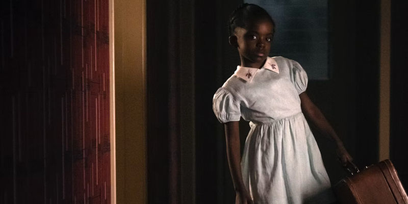 A young girl holds a suitcase in Them season 1