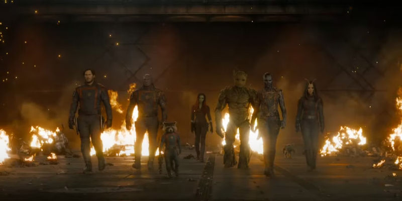 The Guardians of the Galaxy team epicly walks towards the camera as fires burn behind them.
