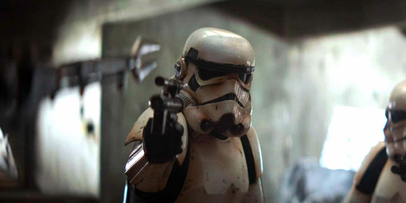 A stormtrooper in The Mandalorian season 1, with dirty armor, pointing a blaster at Din Djarin.