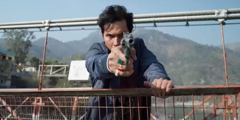 Randeep Hooda as Inspector Avinash Mishra pointing a gun at the camera while standing on a bridge.