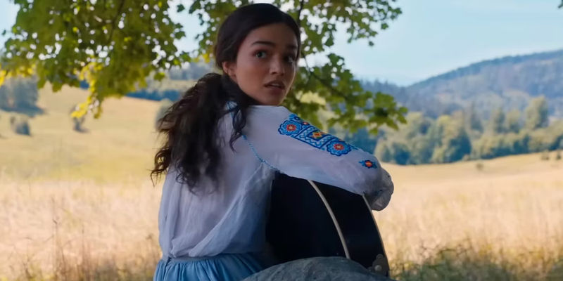 Rachel Zegler as Lucy Gray Baird Turning While Playing the Guitar in The Hunger Games The Ballad of Songbirds and Snakes