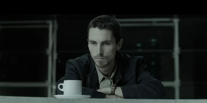 Christian Bale sitting in front of a cup in The Machinist