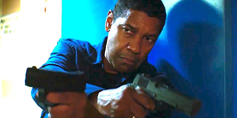 Denzel Washington as Robert McCall holds two guns in The Equalizer 2. 
