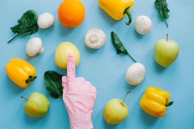 a hand wearing a pink latex glove its pointing out to legumes