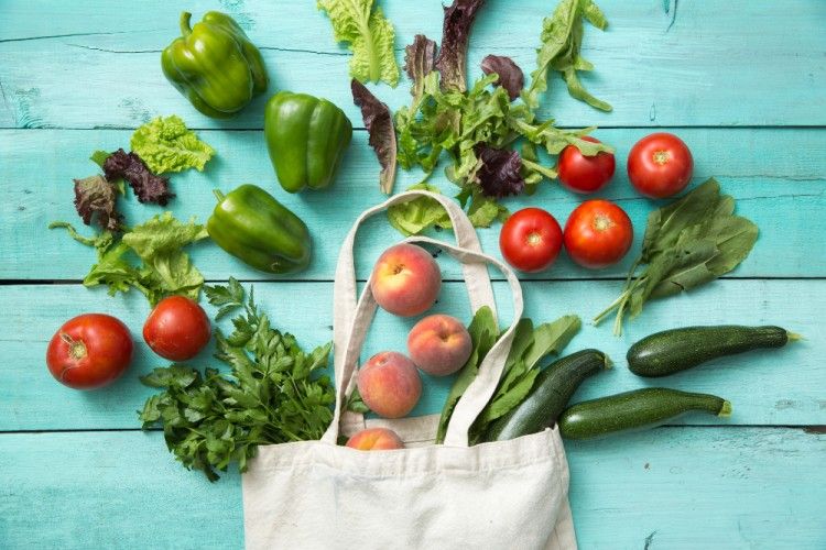 Fresh vegetables burst out of a cloth shopping bag