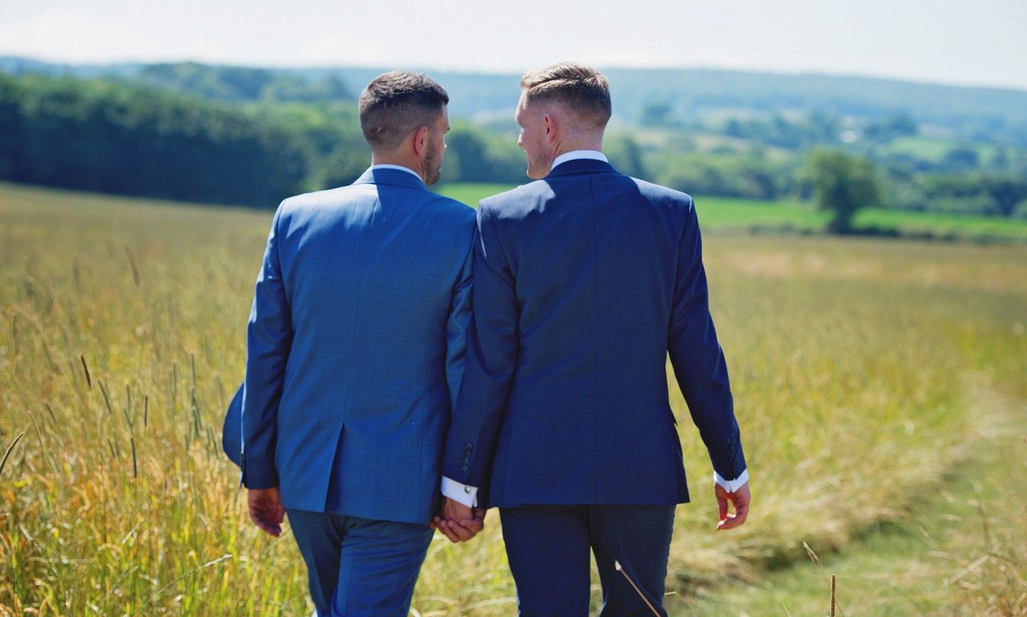 gay male couple holding hands in a field