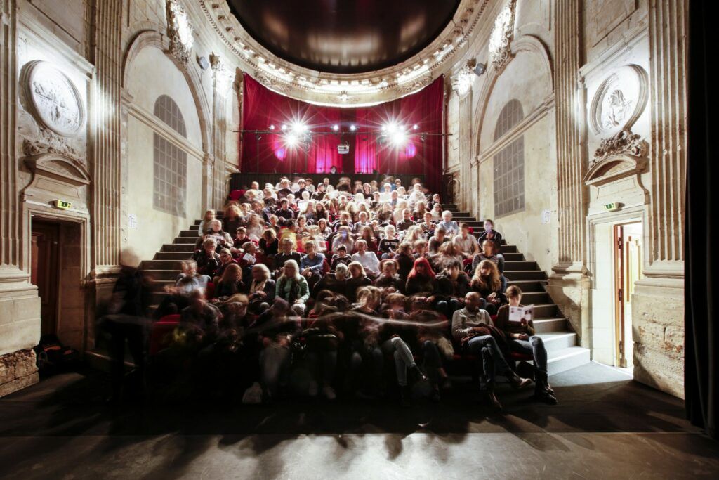 L’intérieur de la salle de spectacles de la Chapelle Saint-Louis. Salle pleine et illuminée.