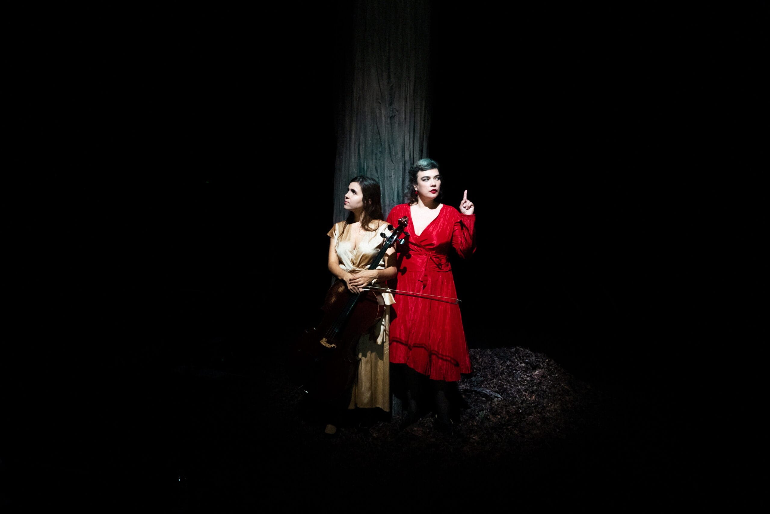 Deux femmes en robe dans un décor sombre.