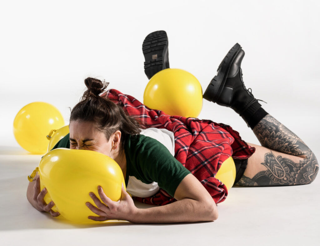 Une jeune femme en kilt s'allonge sur des ballons de baudruche.