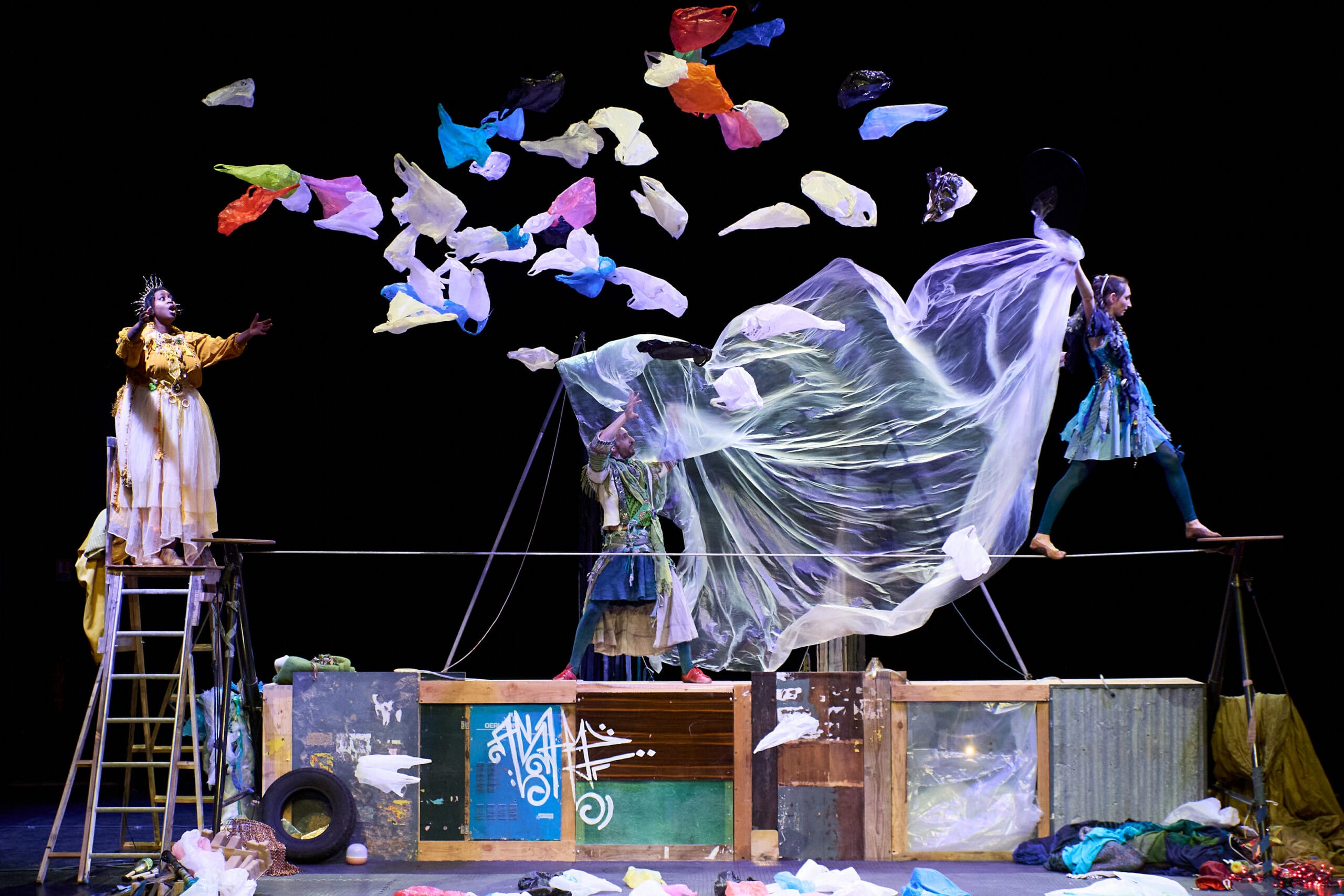 deux femmes costumés dans un décor rempli de plastique coloré et autre débris.
