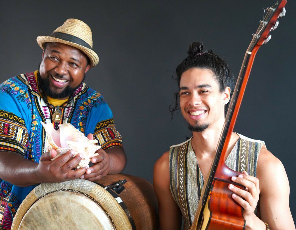Le percussionniste pose avec un coquillage et son instrument. Le guitariste tient son instrument dans la main.