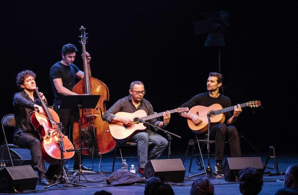 un violoncelliste, un contrebassiste et deux guitaristes sont alignés sur scène