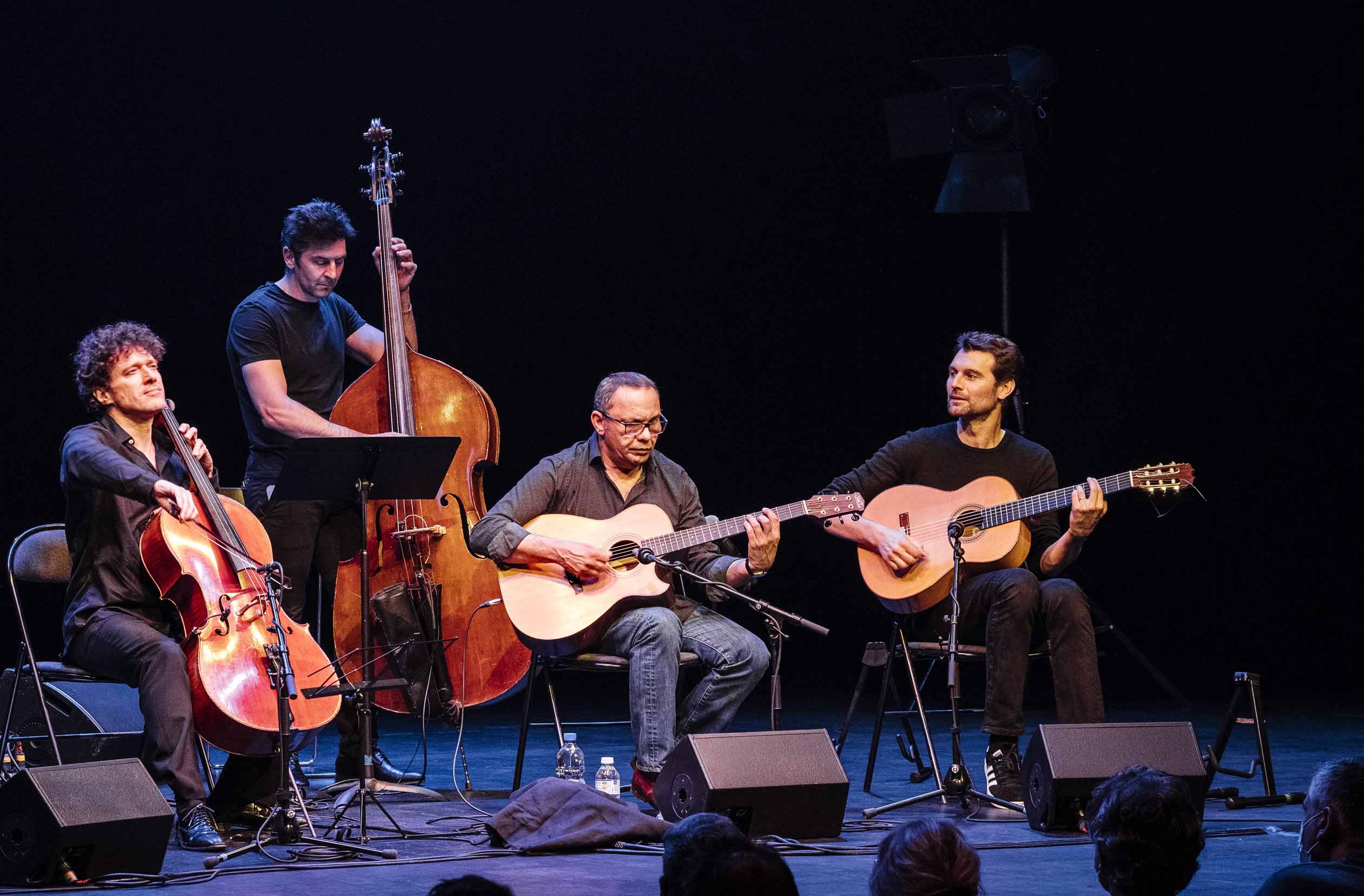 un violoncelliste, un contrebassiste et deux guitaristes sont alignés sur scène