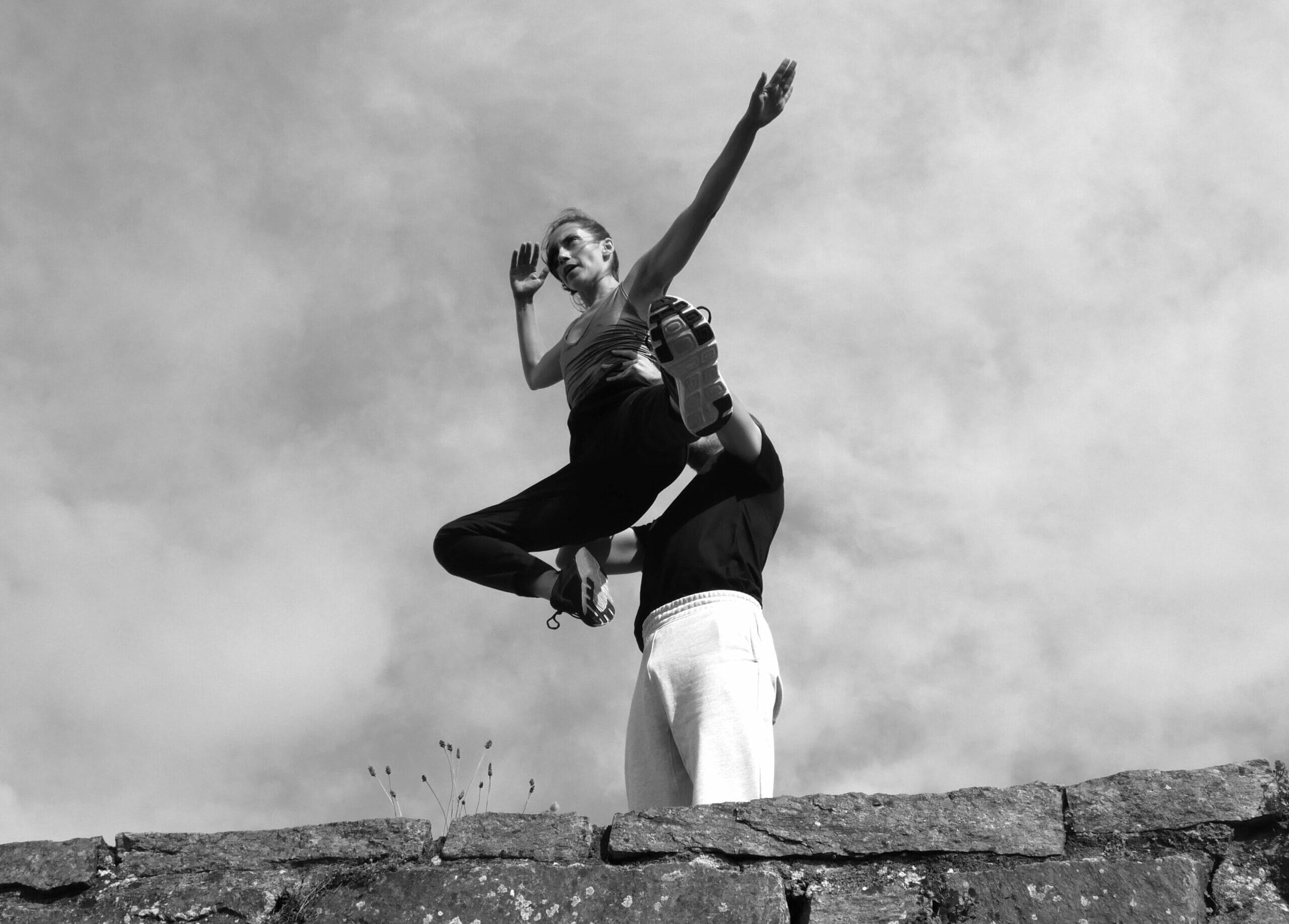 un homme porte une danseuse en mouvement devant le ciel.