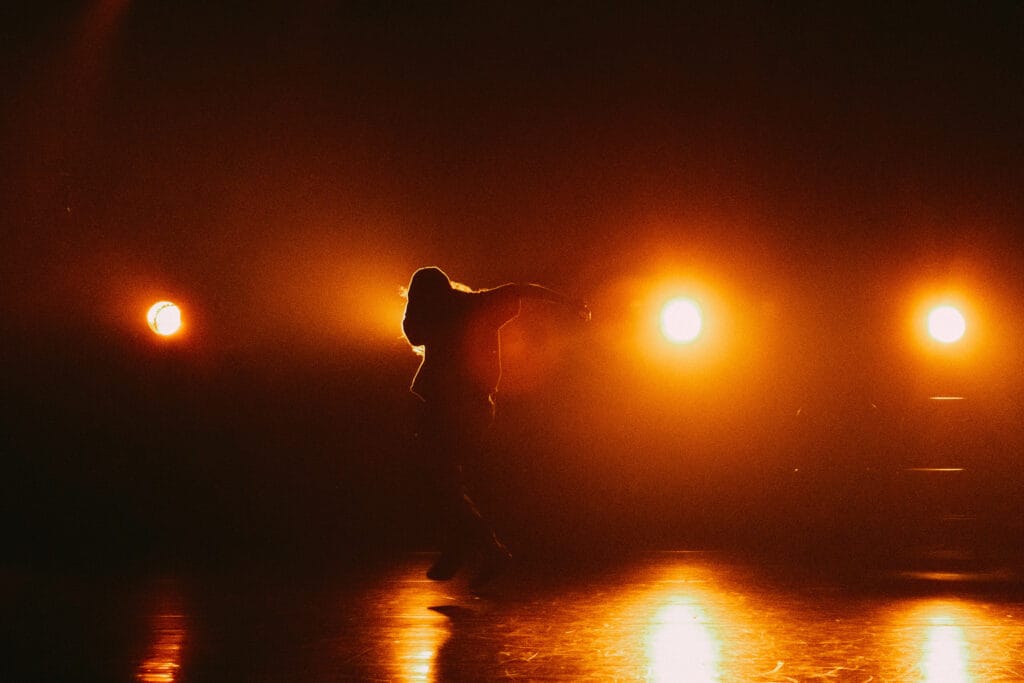 Une silhouette sur scène avec éclairage orange dans le fond