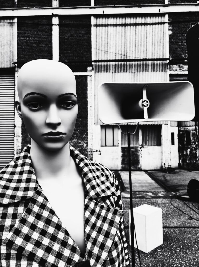 Un mannequin portant une veste à carreaux à côté d'un Haut-parleur vintage.