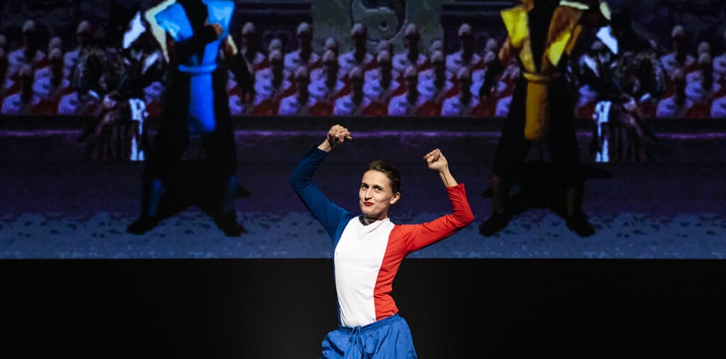 Femme habillée en Bleu blanc rouge devant un écran de jeu vidéo de combat.