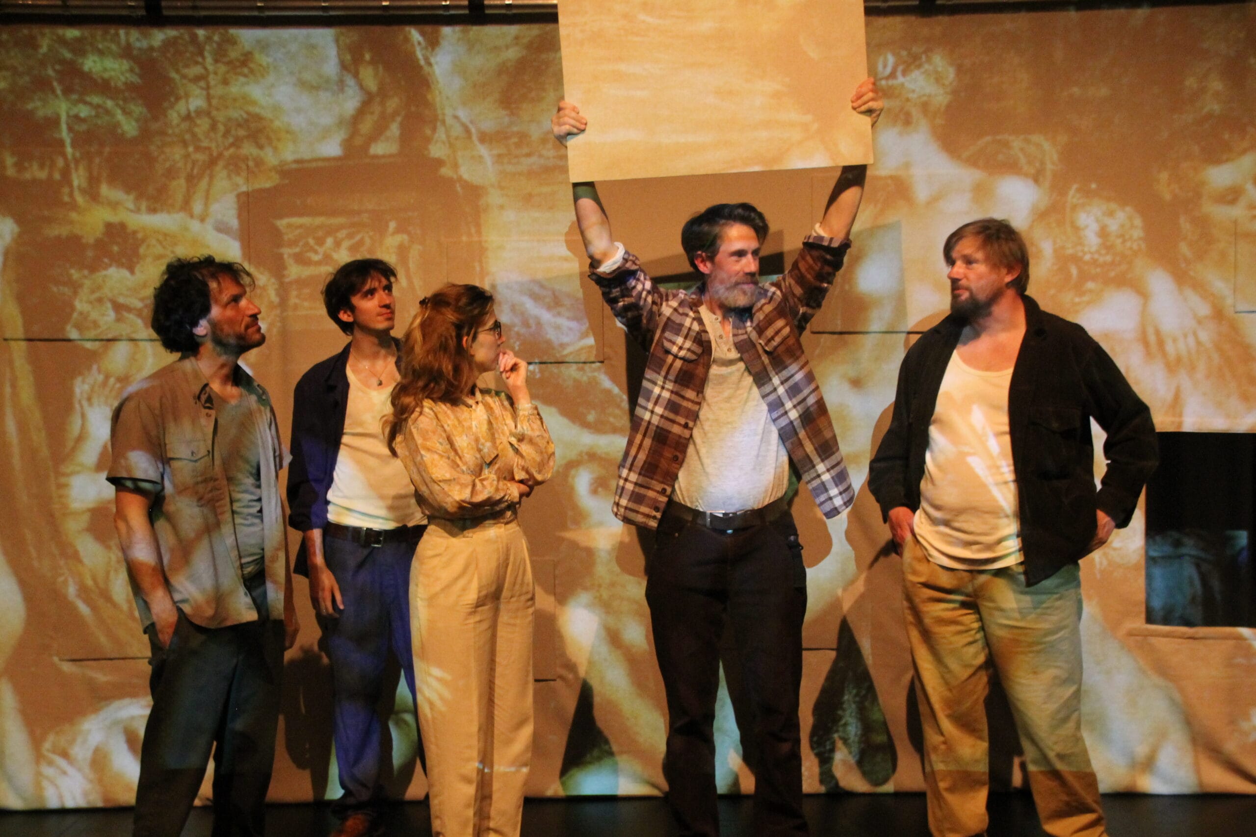 cinq personnages sur scène debout devant un écran avec des peintures projetées.