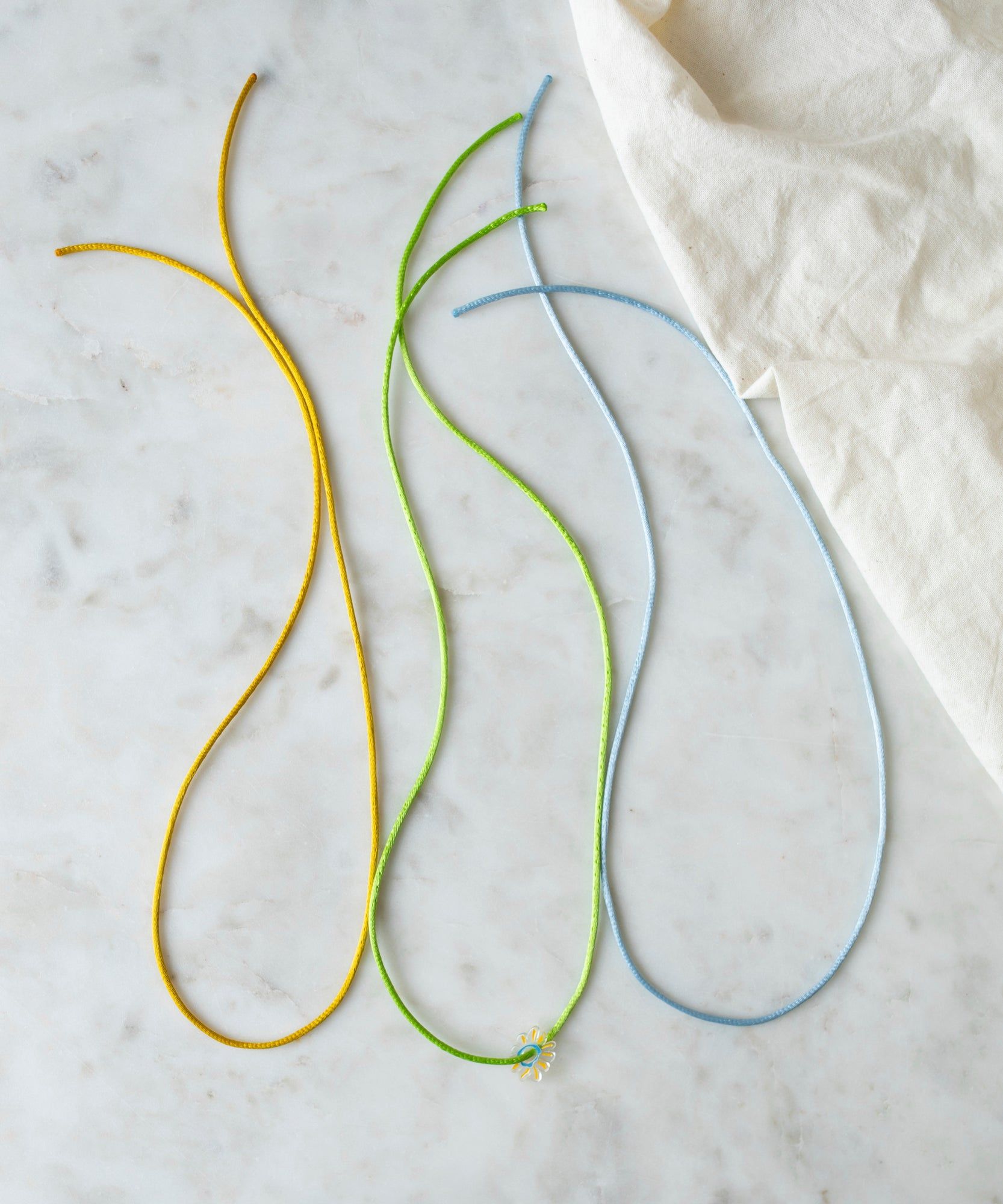 Three WALD World Ribbon Kit Bunt arranged in curved lines on a marble surface, with pendants partially visible.