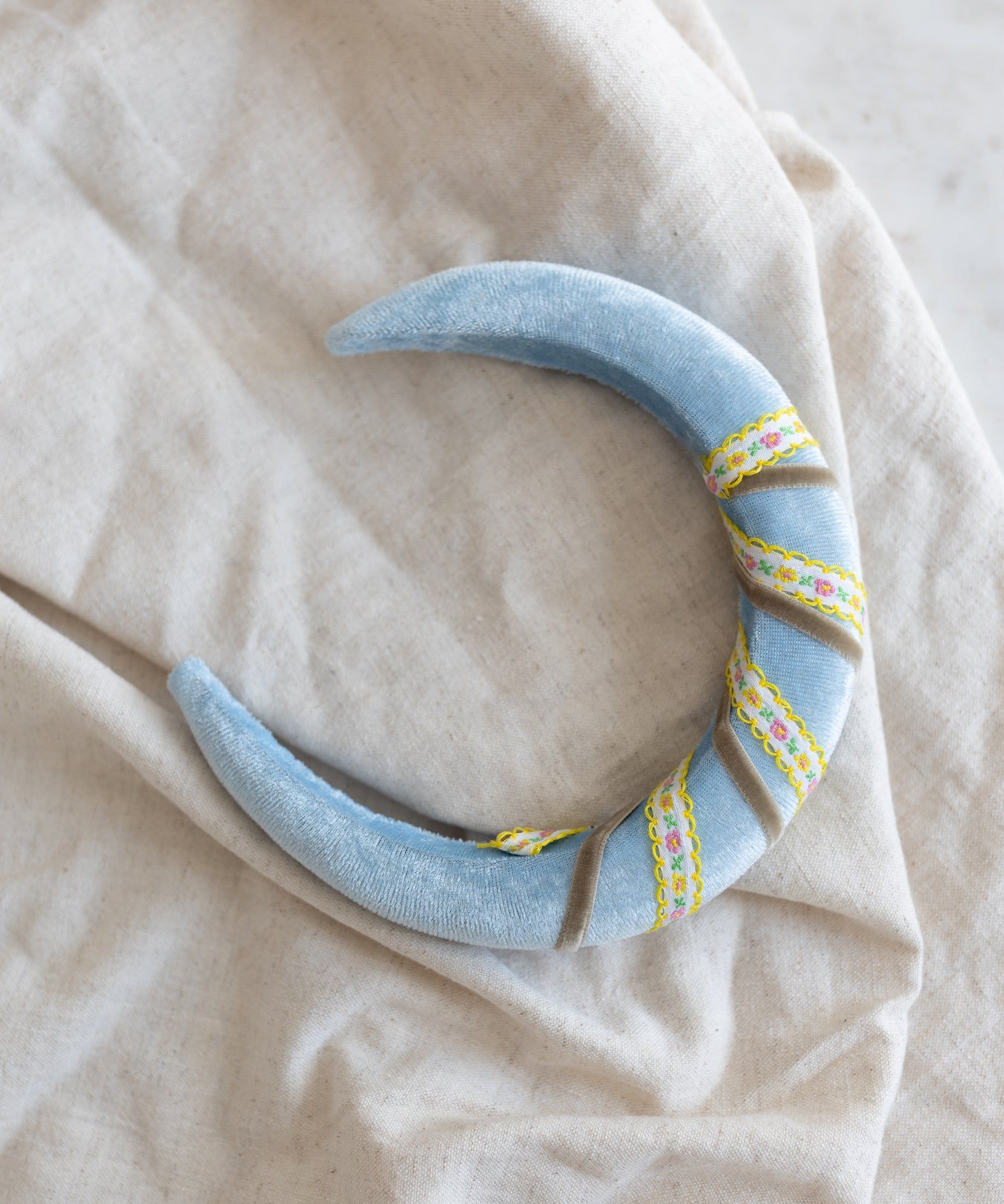 A WALD Berlin Headband Swirl Light Blue on a bed.