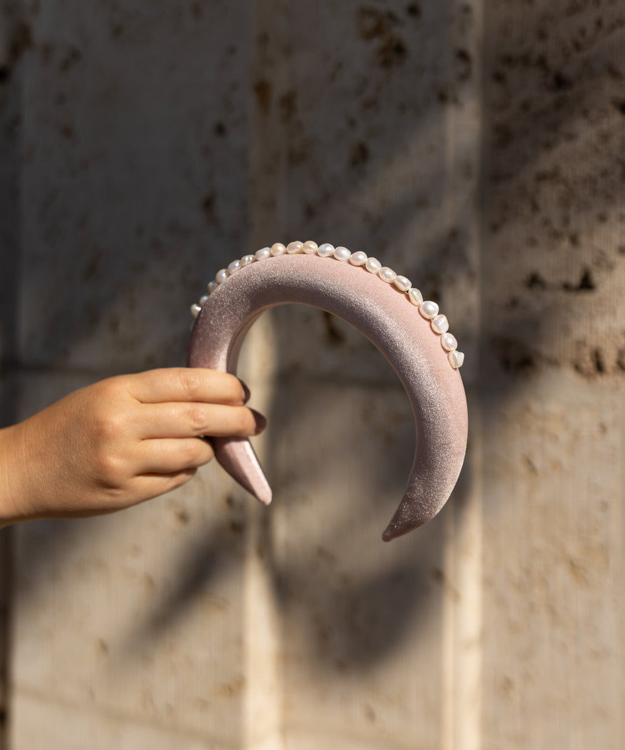 A person's hand holding a WALD Berlin Lady Di Headband Rose.