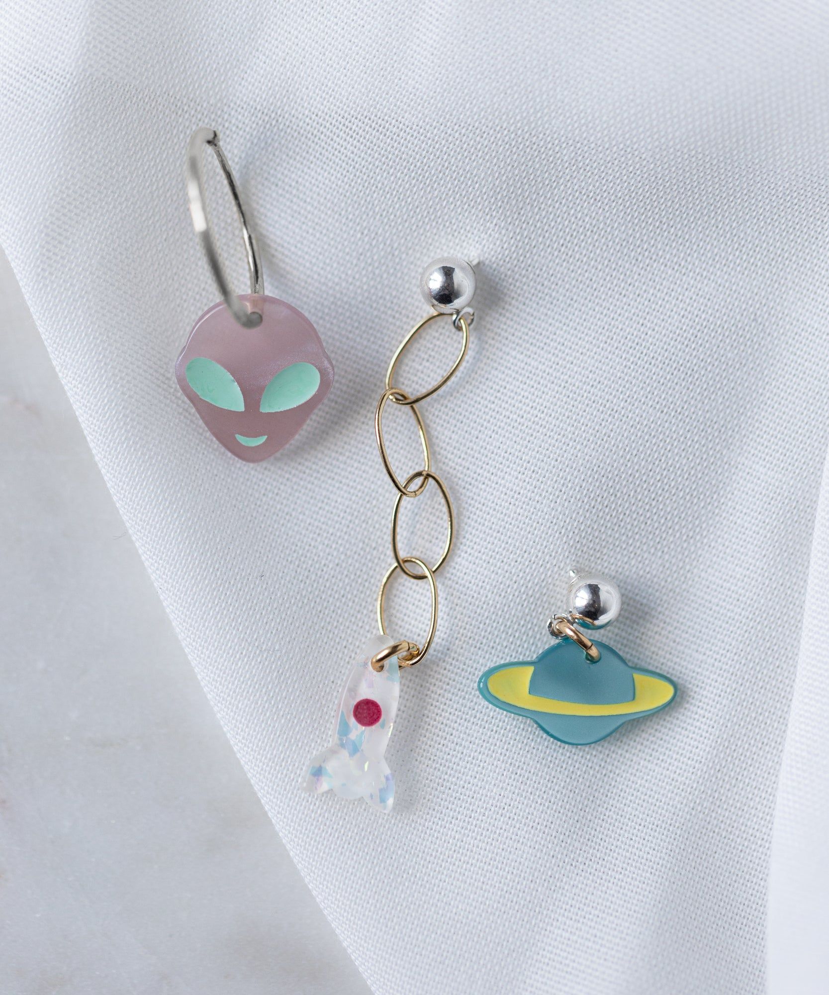 A pair of From Another Mother Galactic Earring Set earrings with aliens and planets on them from WALD Berlin.