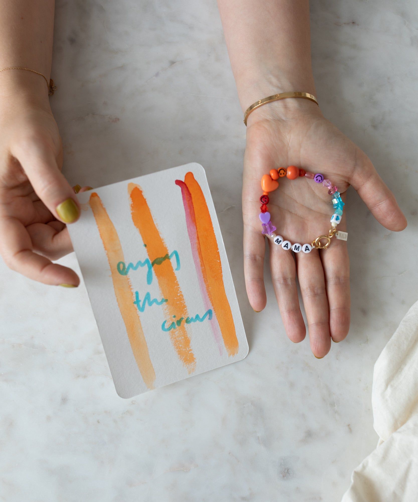 Hands holding a card with colorful stripes and the words 