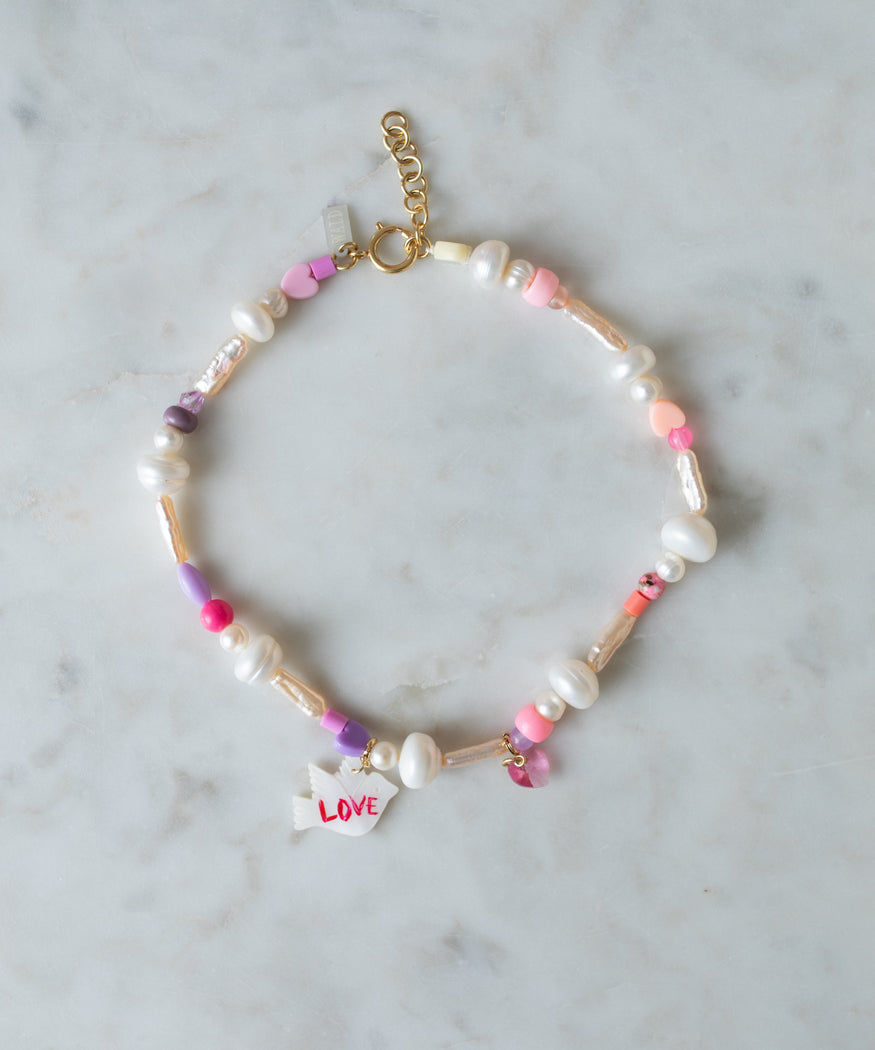 An Imagine Peace Necklace by WALD Berlin with multicolored beads, pearls, and a small charm inscribed with 