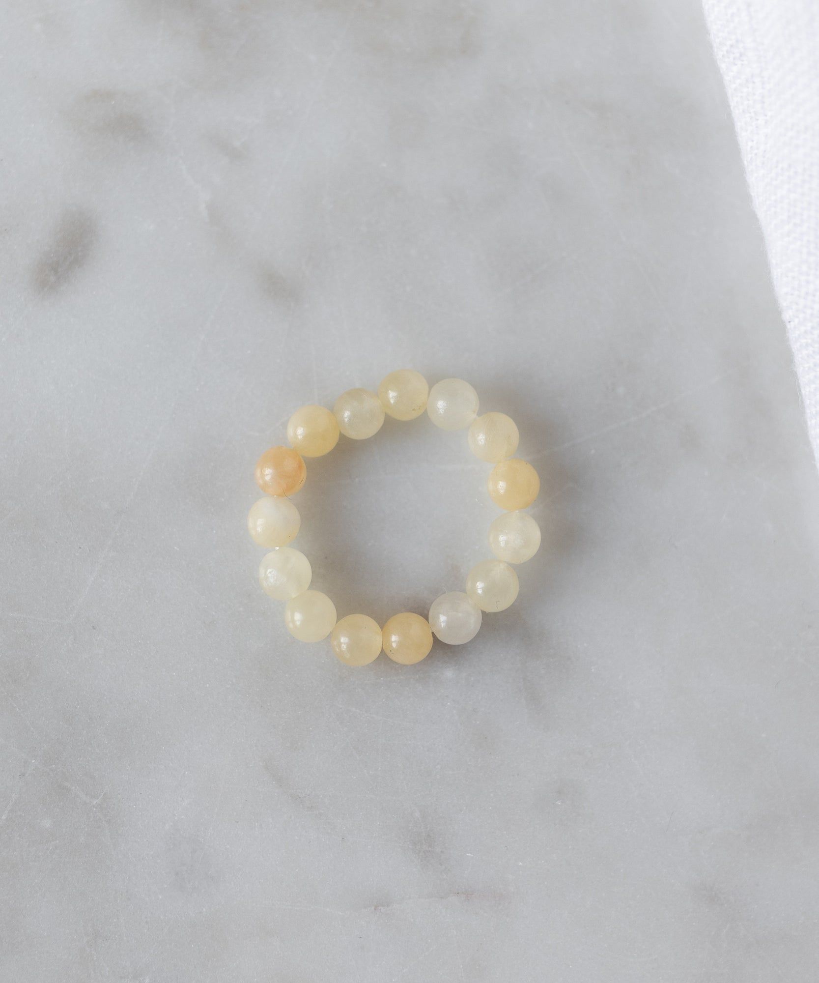 The WALD Berlin Pop Gemstone Ring Set features round, translucent yellow stones and an adjustable fit, displayed on light gray marble—perfect for unique gift ideas.