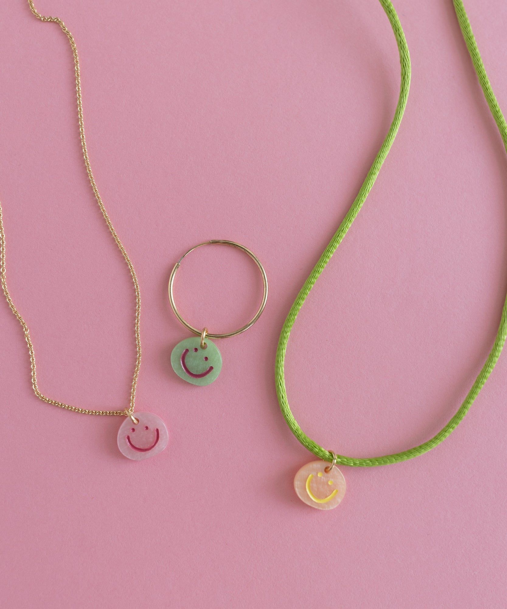 Two DIY Charm necklaces and a ring with a smiley face on them.