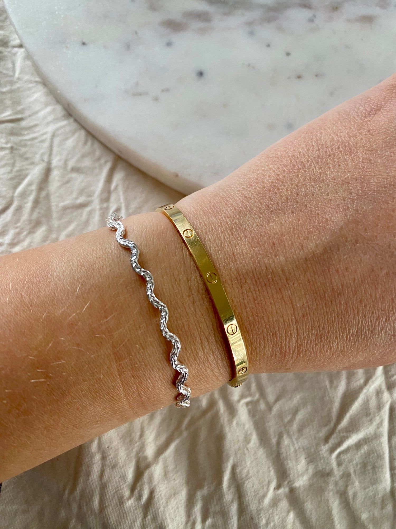 A woman's hand with two WALD Berlin Irina Bracelet Silver bracelets.