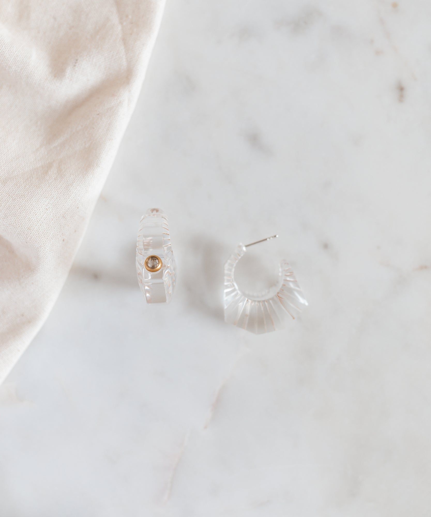 A pair of WALD Berlin crystal earrings prominently displayed on a marble table in Germany.