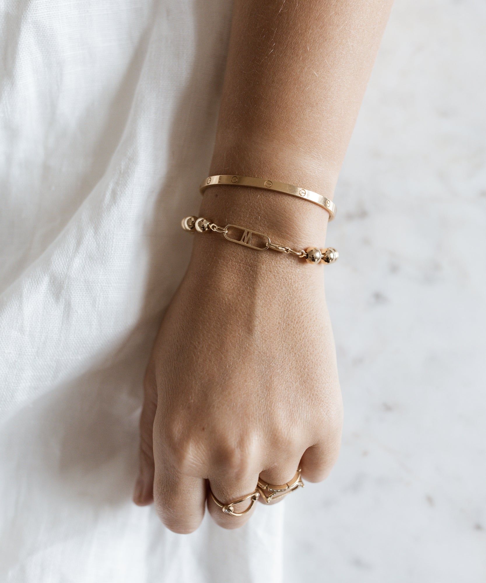 A woman's hand with two WALD Berlin Harry Gold Bracelets on it.