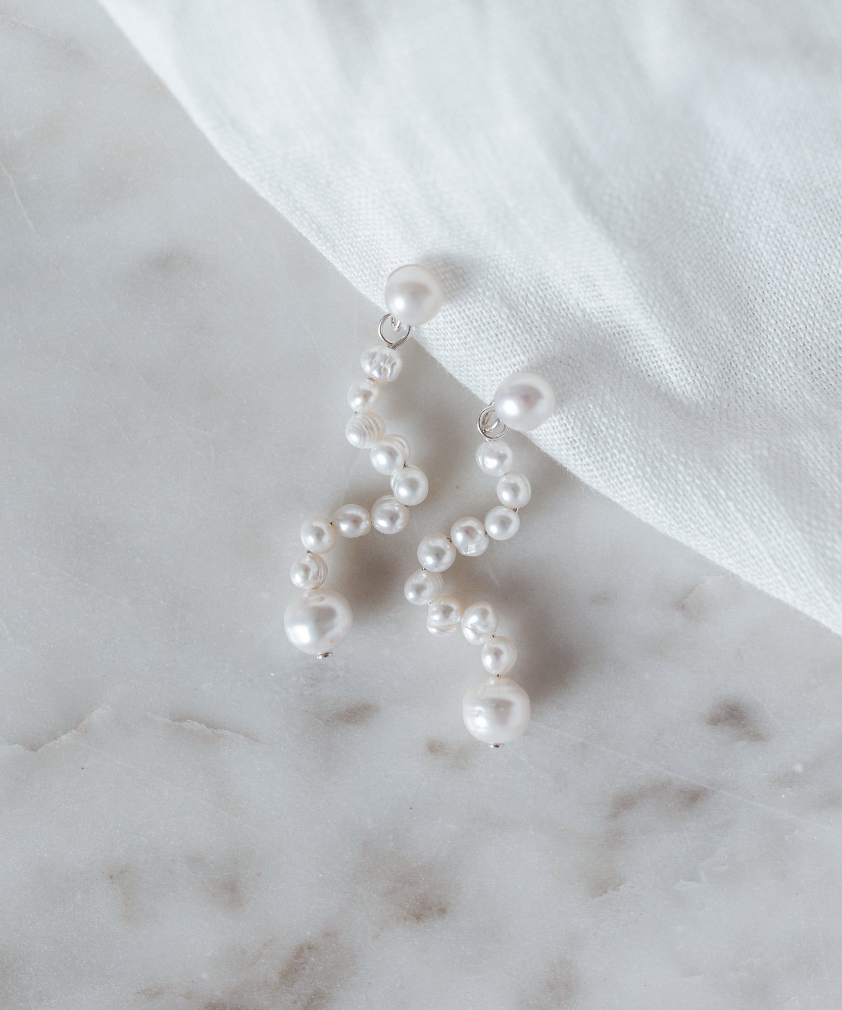 A pair of Happy La Rêve Earrings from WALD Berlin displayed on a marble table in Germany.