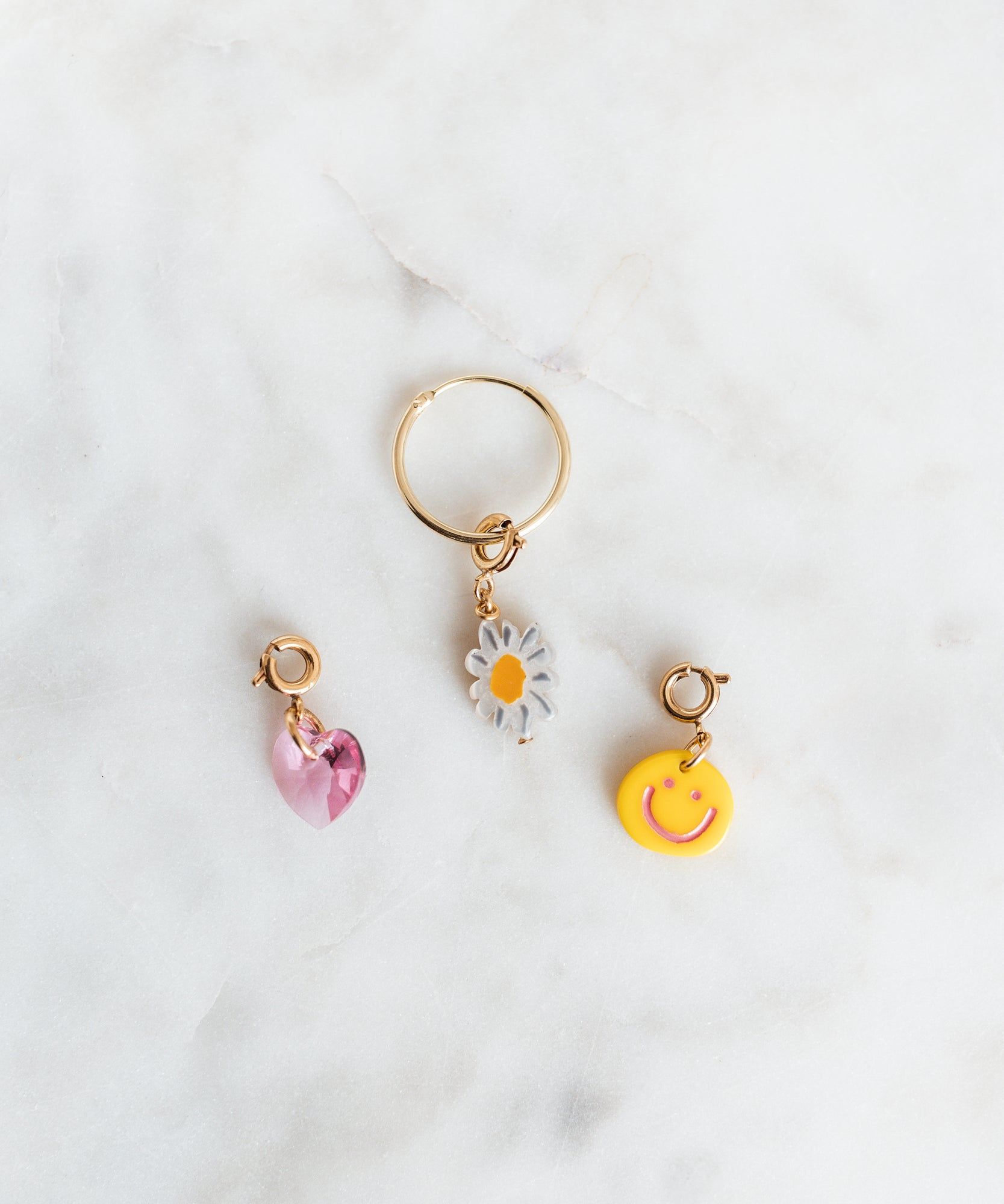 A set of WALD Berlin gold hoop earrings with WALD x Frollein Herr Charms featuring a flower and a smiley face.