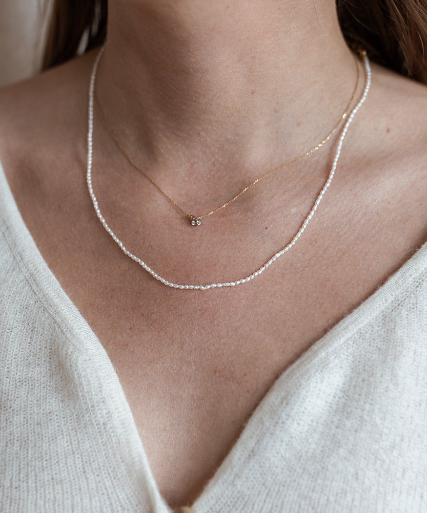 A woman is wearing a WALD Berlin Fine Rice Pearl Necklace, showcasing exquisite jewelry from Germany's capital city.