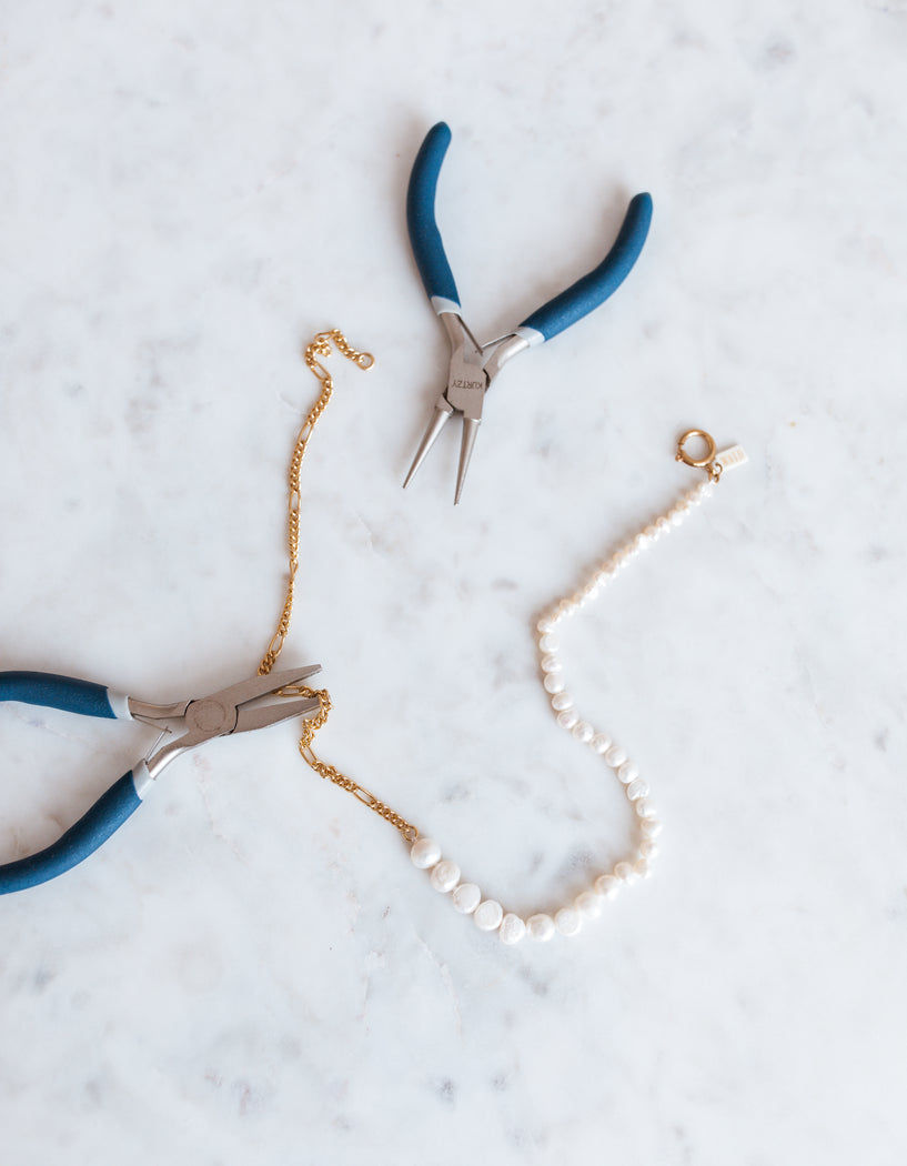 A pair of WALD Berlin pliers and a WALD Berlin pearl necklace on a table in Germany.