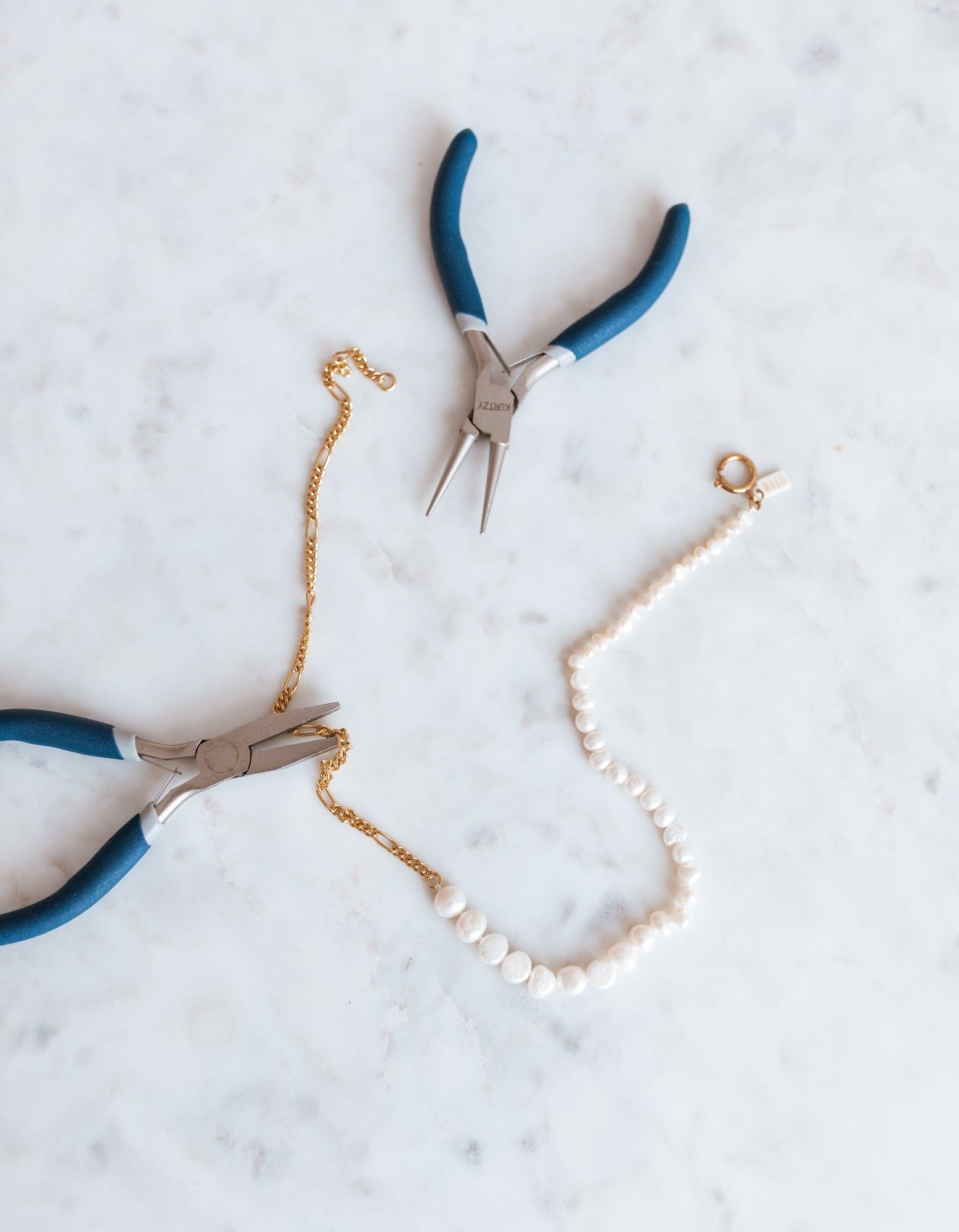 A pair of WALD Berlin pliers and a WALD Berlin pearl necklace on a table in Germany.