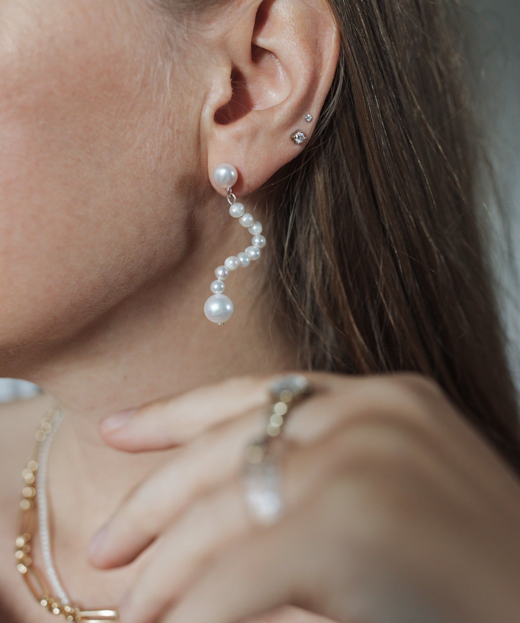 A woman wearing Happy La Rêve Earrings by WALD Berlin and a gold ring in Germany.