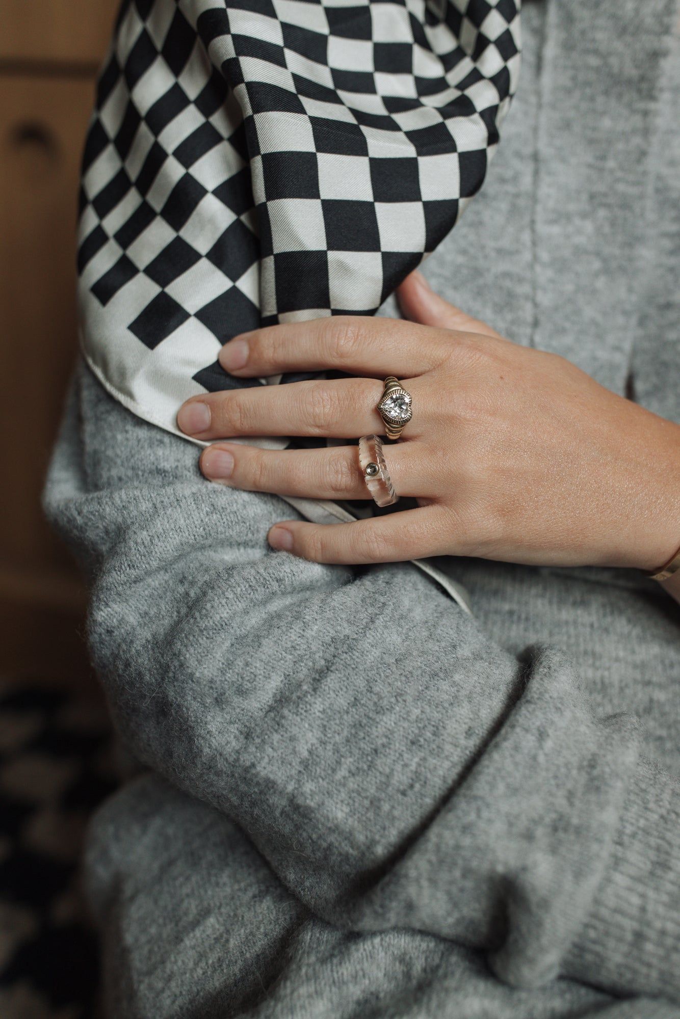 A woman wearing a checkered scarf and Be My Lover Gold Ring by WALD Berlin.