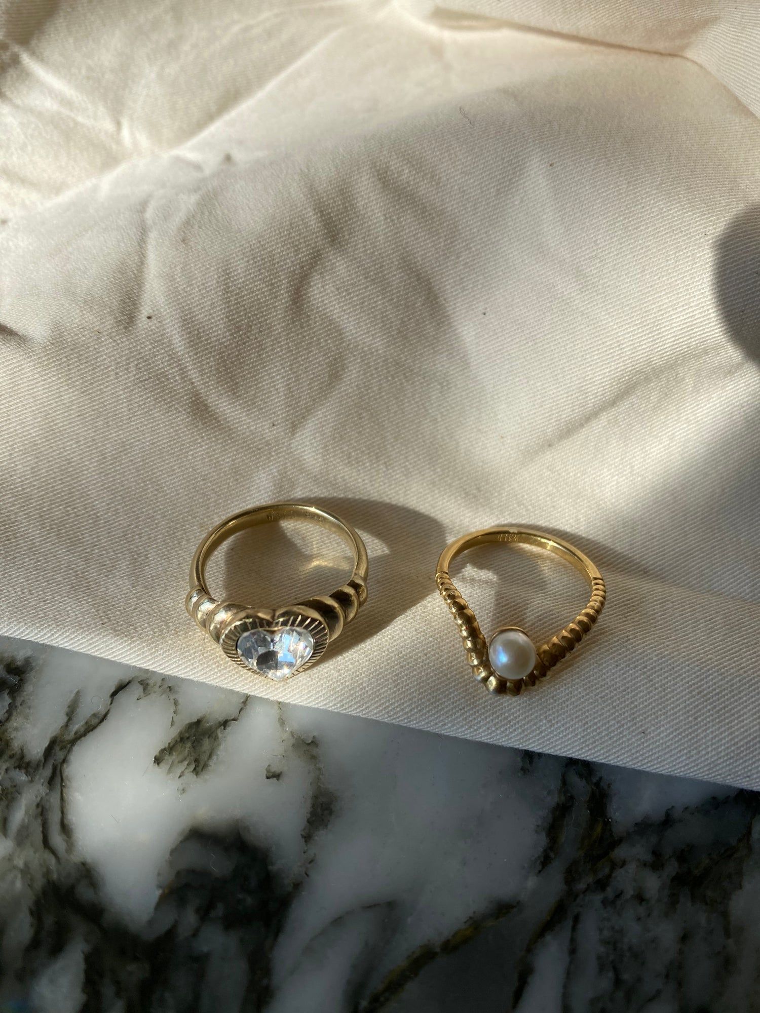 Two WALD Berlin NYC If I Rule The World rings with pearls on top of a recycled marble table.